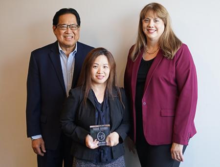 Three executive employees pose with an award from Personify Health in a conference room with a nationalprimepay Bank logo displayed.